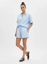 Short de tiro alto con cintura elástica, confeccionado en tejido plano a rayas verticales celestes y blancas. Presenta un acabado foil que le da un efecto brillante.