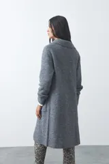 Cardigan de tejido de punto gris, con silueta larga, frente abierto, solapas clásicas y bolsillos aplicados en los laterales.