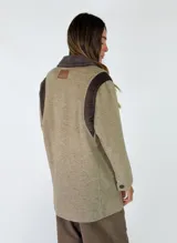 Tapado de paño de lana en color beige con detalles en pana marrón oscuro en hombros, cuello y bolsillos. Diseño de corte recto y estructura clásica.