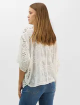 Cardigan abierto estilo kimono, color crudo, con mangas amplias al codo. Presenta una base con textura y motivos florales bordados a tono, con paneles de encaje calado estilo macramé en el frente, puños y ruedo.