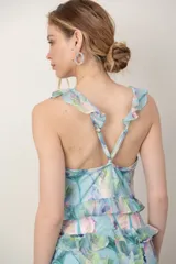 Vestido largo de gasa verde agua con estampado floral en tonos pastel, escote en V profundo, espalda cruzada con tirantes regulables y detalles de volados en los tirantes y en el ruedo.