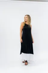 Vestido largo negro con base blanca, de corte suelto y sin mangas.