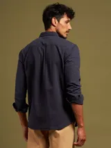 Camisa de manga larga color azul con dos bolsillos frontales con botón.