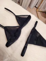 Conjunto de lencería compuesto por un corpiño triangular de microtul transparente con detalles de encaje en las copas y una tanga regulable con elástico ancho.