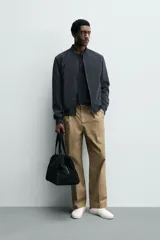 Cazadora bomber ligera de tejido técnico color verde oliva, con cuello, puños y bajo en rib elástico. Presenta cierre frontal de cremallera y bolsillos de vivo en la cadera.