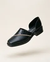 Zapato de cuero negro con diseño de punta cuadrada, laterales abiertos y costura artesanal en hilo beige a contratono. Cuenta con taco bajo.