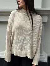 Sweater color crema con cuello alto y diseño de trenzas.