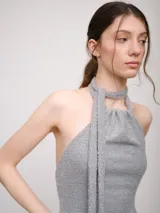 Vestido corto color marrón, con escote halter y tiras largas que se anudan al cuello estilo choker. Presenta un diseño con jareta en el escote y falda acampanada.