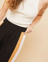 Pantalón palazzo color beige con cintura elastizada y dos franjas verticales en los laterales, una plateada y otra blanca.