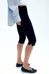Pantalón capri de tiro medio en color negro, con detalles de tapetas frontales, aberturas laterales en el bajo y cierre lateral con cremallera oculta.