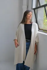 Poncho abierto de tejido de punto color crudo, con mangas tres cuartos y bolsillos frontales aplicados.