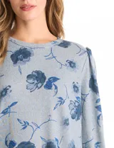 Buzo de tejido soft con estampado floral en tonos azules, cuello redondo y mangas largas con puños fruncidos.