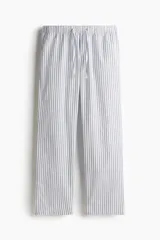Pantalón de popelina de algodón a rayas blancas y negras, con cintura elástica y cordón ajustable. Presenta bolsillos laterales y un corte relajado.