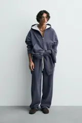 Pantalón jogger de corte wide fit confeccionado en algodón con interior de rizo. Presenta cintura elástica ajustable con cordón, bolsillos laterales y un bolsillo trasero de plastrón. Cuenta con un efecto lavado y acabados irregulares en el ruedo.