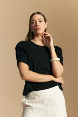 Remera blanca de cuello redondo con mangas cortas abullonadas y detalle de nudo en los puños.