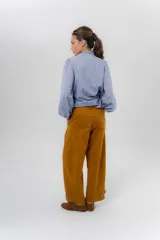 Pantalón de gabardina de algodón color negro, con calce barrel, cintura media baja, recortes de diseño y detalle de botones en el ruedo para ajustar el volumen.