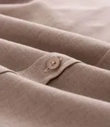 Camisa de manga larga confeccionada en tricolina de algodón, con cuello inglés, cierre frontal de botones y puños abotonados. Diseño liso y versátil.