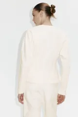 Buzo de felpa color beige con cuello redondo acanalado, mangas largas raglán y costuras moldeadoras en la cintura que crean una silueta entallada.