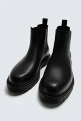 Bota tipo Chelsea de cuero color marrón oscuro, con paneles elásticos laterales, tirador trasero y suela track con volumen.