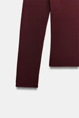 Jersey de punto color bordó, con escote barco de hombros descubiertos y manga larga.