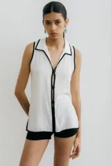 Blusa negra sin mangas con cuello camisero y abertura a los costados, con ribete color beige.