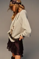 Falda pantalón de tiro medio color marrón oscuro, con frunces laterales y volantes en el bajo. Incluye un cinturón ancho decorado con círculos metálicos y remaches dorados.