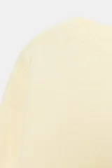 Jersey corto de punto liso color marfil, con cuello redondo, manga larga y dobladillo asimétrico más corto en la parte frontal.