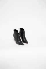 Bota corta de cuero negro con punta fina y taco aguja. Diseño minimalista con cierre lateral interno.