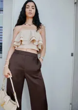 Pantalón de corte recto y tiro medio, confeccionado en tejido satinado color marrón oscuro. Presenta cintura con elástico, bolsillos laterales y una sutil raya lateral en contraste.