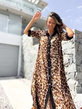 Vestido midi con estampado animal print de leopardo en tonos beige y marrón, con cierre frontal de botones y detalles en color negro en el cuello, mangas y borde central.