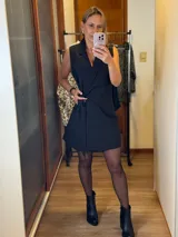 Chaleco vestido color rosado, de corte recto, sin mangas, con cuello tipo blazer y lazo para atar en la cintura.