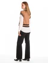 Buzo combinado de estilo preppy que simula un conjunto de sweater tejido con camisa debajo. Presenta un cuerpo de punto color marrón con escote en V y ribetes negros en cuello, sisas y ruedo, integrado con cuello, mangas largas y bajo de gasa blanca.