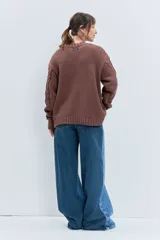 Sweater de punto color celeste, con diseño de trenzas y detalles de cordones entrelazados en el frente y las mangas. Presenta cuello redondo y puños acanalados.