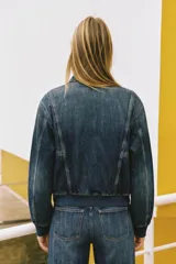 Campera bomber de denim en color gris oscuro con efecto lavado, cuello camisero, cierre frontal de cremallera metálica, bolsillos laterales ribeteados y terminaciones elásticas en puños y cintura.