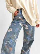 Jean wide leg de tiro alto con estampado de flores y hojas verdes, de corte amplio y cómodo.