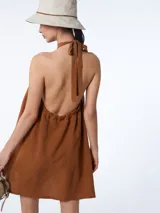 Vestido corto azul marino de tencel con corte evasé, cuello halter con lazo ajustable y espalda descubierta.