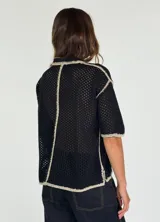 Chaqueta amarilla de tejido calado con cuello camisero, cierre con botones y bolsillo de parche en el pecho.