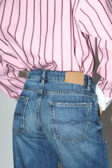 Jeans de tiro alto con corte recto y diseño de cinco bolsillos. Presenta un lavado azul clásico con efecto desgastado y cierre frontal con cremallera y botón metálico.