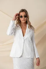 Blazer de corte sastre en color blanco, confeccionado en crepé satén con detalles de flecos de seda en toda la prenda. Presenta solapas clásicas, cierre frontal con botón de nácar y dos bolsillos laterales tipo ojal.
