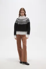 Sweater de punto con diseño jacquard en cuello, puños y ruedo. Presenta cuello alto, mangas largas y corte holgado.