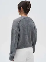 Cardigan de punto color gris, con cierre frontal completo, cuello redondo y diseño de manga larga con hombros caídos.