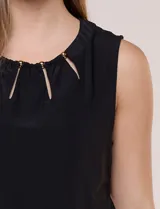 Blusa blanca de seda fría, sin mangas, con escote redondo, frunces sutiles y pequeñas aberturas verticales sujetas por cuentas metálicas doradas.