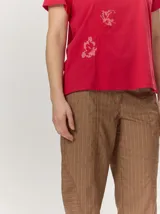 Remera negra de manga corta con cuello redondo y detalle de bordado floral en tono tostado en la parte inferior derecha.