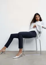 Pantalón de vestir azul marino, de corte skinny y diseño crop de tiro medio, con trabillas, bolsillos laterales y cierre frontal de cremallera y botón.