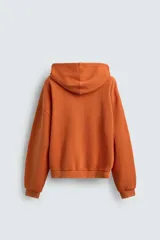 Sudadera tipo hoodie de corte relajado, confeccionada en tejido de algodón con textura estructurada y efecto lavado. Presenta cierre frontal con cremallera, cuello con capucha, manga larga, bolsillos tipo canguro y acabados en rib.