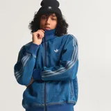Campera adidas Adicolor Firebird de denim azul, con cierre frontal, bolsillos laterales, cuello alto y las icónicas tres tiras de la marca en las mangas.