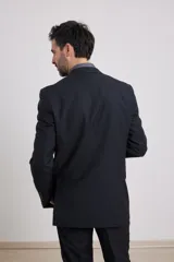 Traje de corte clásico compuesto por saco de dos botones y pantalón de vestir a juego. El saco presenta solapas tradicionales y bolsillos con solapa, mientras que el pantalón tiene un corte recto y formal.