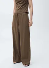 Pantalón de tiro medio color marrón, con diseño recto y holgado, cintura elástica con cordón ajustable y bolsillos laterales.