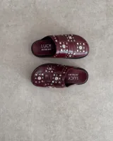 Zuecos color borgoña con apliques de tachas plateadas.