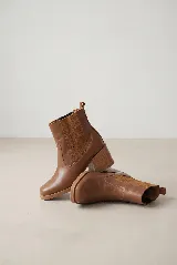 Bota corta tipo chelsea de cuero color suela, con paneles laterales de gamuza al tono y taco cuadrado foliado en madera de 6 cm.